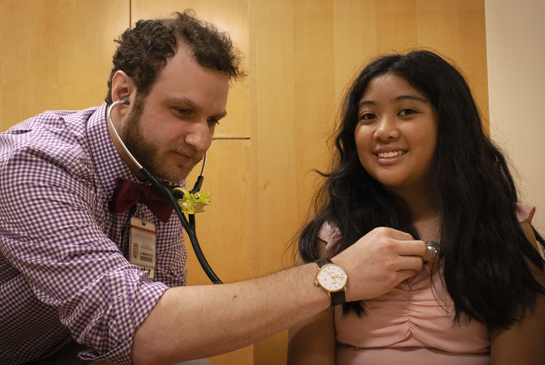 doctor listening to heatbeat on a patient in a clinic room