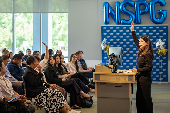 A speaker at a conference in front of an audience of nurses.