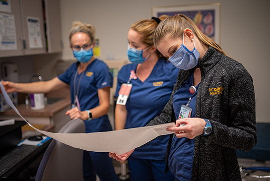 3 Nurses looking at a fetal monitoring paper.