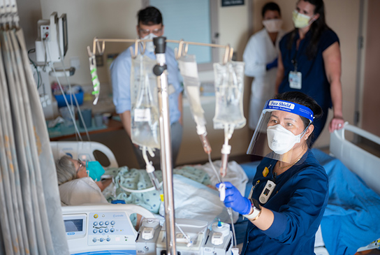A nurse adjusting an IV drip in a patient's room.