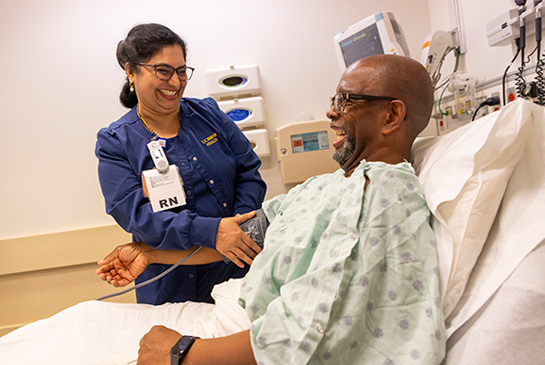 Nurse applying a blood pressure cuff to a man's arm in bed