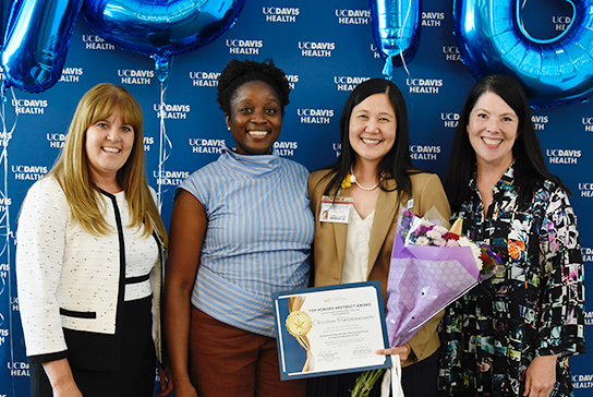 4 Nurses posing for photo with UC Davis background.