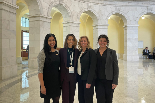 Four women smile inside a rotunda at the U.S. Capitol building.