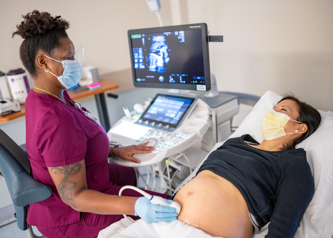 Nurse performing ultrasound on pregnant patient