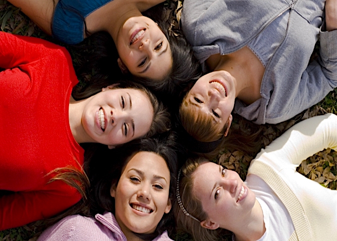 group photo of young women laying on the ground together smiling