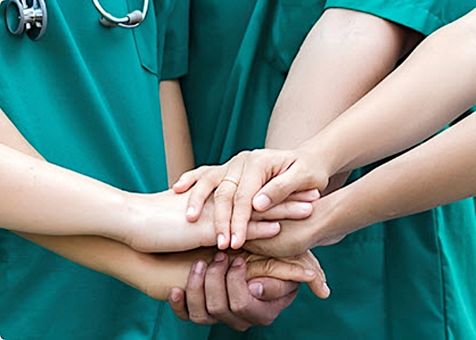 cropped image of doctors stacking their hands on top of one another