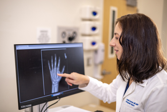 Doctor looking at a hand xray on a screen