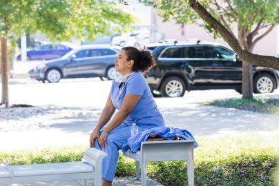 a female hospital worker sitting on a bench outside 