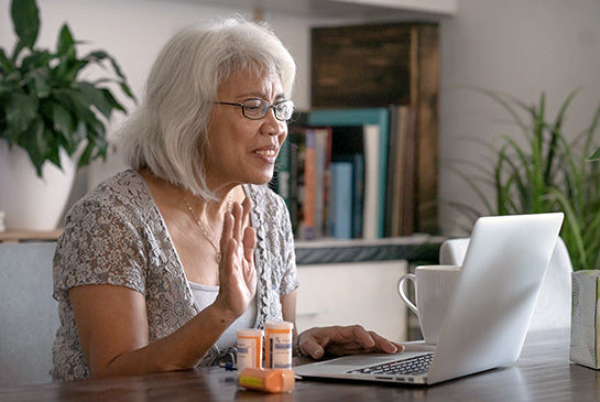 Elderly woman on laptop telehealth appointment to talk about medications