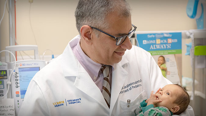 Dr. Satyan Lakshminrusimha holding neonatal baby in arms.