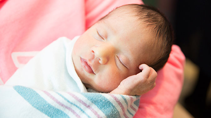 Neonatal baby named Alexander, sleeping in covers in NICU.