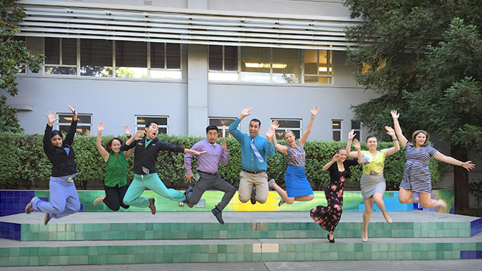 Nine residents pose for photo mid jump in air.