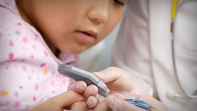 Checking young patient's blood glucose levels