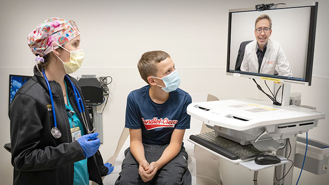 young patient in a doctor's office having a telehealth video visit with a consulting doctor