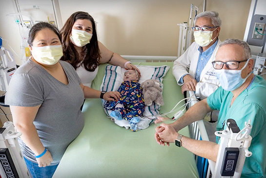 Pediatric cardiology doctors with Mom and infant in ICU
