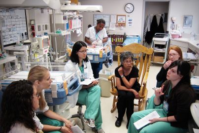 Doctors and residents discuss pediatric medicine in normal newborn nursery.
