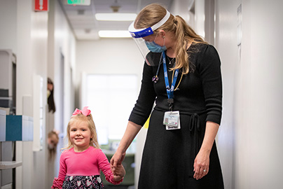 Pediatric gastroenterologist with young patient walking down a hospital hall