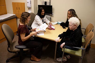 Pediatric adolescent and mother meet with genetic counselor and doctor at the MIND clinic.