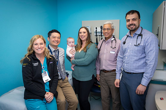 Cardiology team, two physicians and one nurse, with pediatric infant and mother