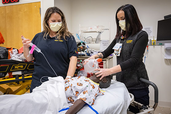 Pediatric Transport staff training with patient dummies in bed simulating medical procedures for training purposes
