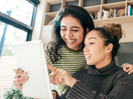 two women looking and pointing at a tablet together