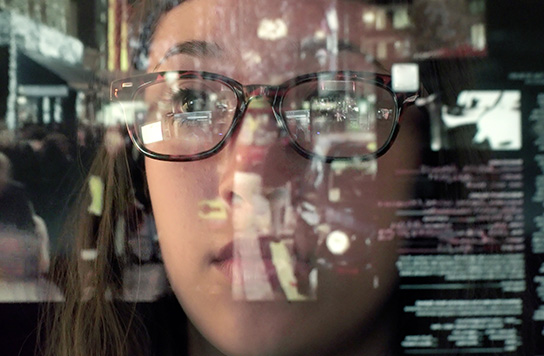 A woman's face with a computer screen reflected