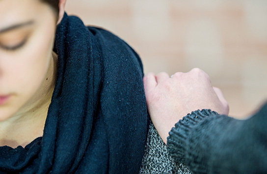Young woman with a comforting hand on her shoulder