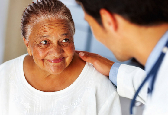 Doctor with hand on the shoulder of smiling female patient