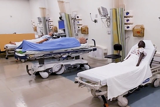 A room with hospital beds, mannequins and equipment.
