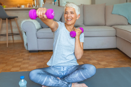 Elderly woman in her living room working out with weights.