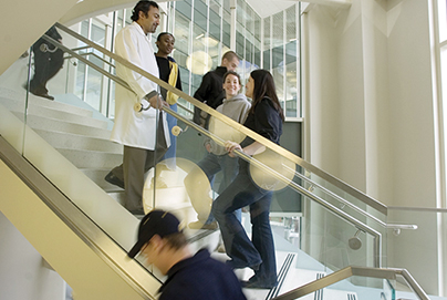 Students meet a teacher on a busy stairway.