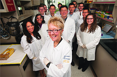 group of scientists in white coats pose in a laboratory