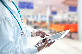person in a white coat holding a digital device