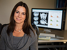 The picture shows professor Diana Miglioretti sitting in front of a computer monitor depicting clinical scans.