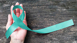This graphic shows a hand holding a teal ribbon symbolizing cervical cancer awarness