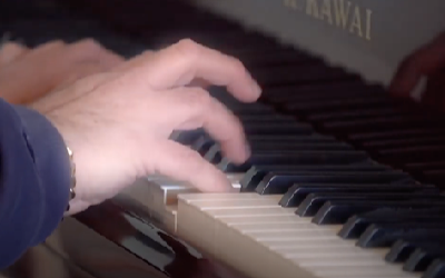 man's hands playing piano