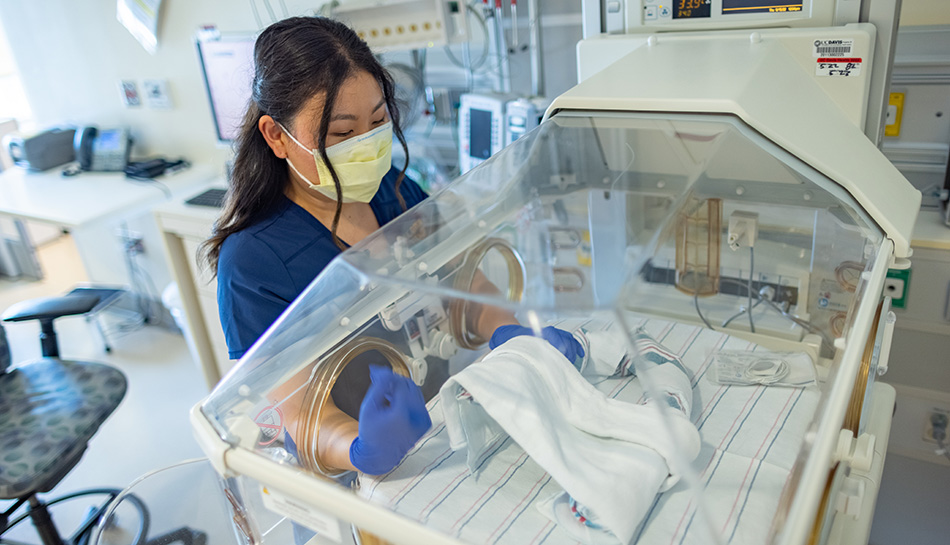 Nurse Ju-A Son prepares an infant bed in the UC Davis Health neonatal intensive care unit. 