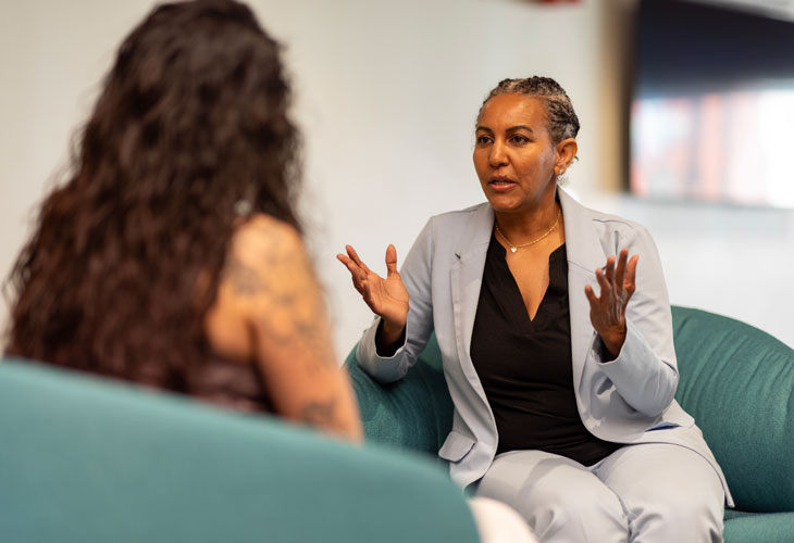 PMHNP Selam Gebrezghi sits in a chair and speaks with a patient
