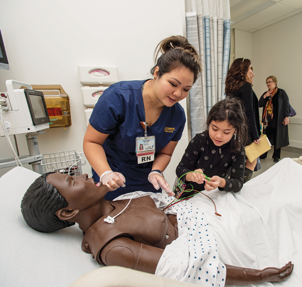 Master’s-degree leadership student Charis Ong shows a guest a mannequin in one of the simulation suites.