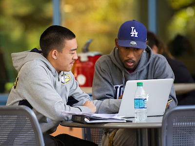two students sitting with laptop studying