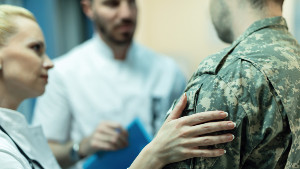 female doctor placing hand on soldier's shoulder to reassure him
