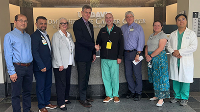 Group of six men and two women in front of the main reception at the cancer center