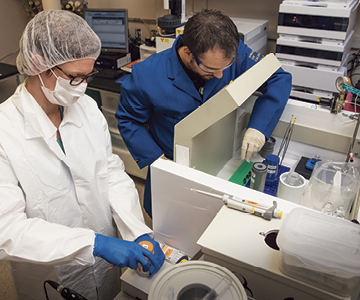 Julie Sutcliffe and postdoctoral researcher Ryan Davis perform quality assurance of radioactive imaging agent.