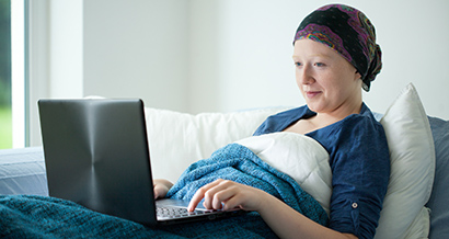 cancer patient laying in bed on the computer