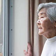 Asian American woman looking out a window