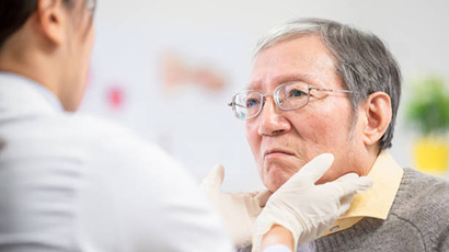 Physician checking an older man's neck